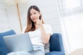 Young asian business woman smile and work from home with laptop computer online to internet on sofa in living room. Royalty Free Stock Photo