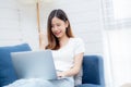 Young asian business woman smile and work from home with laptop computer online to internet on sofa in living room. Royalty Free Stock Photo