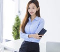 Young  Asian business woman smiling and holding  smart phone  working at the office Royalty Free Stock Photo