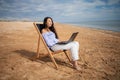 Asian business woman with tablet computer during tropical beach vacation. Freelancer working on laptop lying on sun lounger. Royalty Free Stock Photo