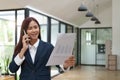 Young asian business woman talk on cellphone discussing paperwork. Royalty Free Stock Photo