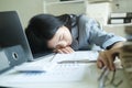 Young asian Business woman tired woman sleeping on desk with laptop at workplace alone. Royalty Free Stock Photo