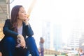 A young Asian business woman in town.She is sitting on walkway.