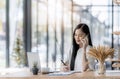 Young asian business woman using laptop and writing on notebook Royalty Free Stock Photo