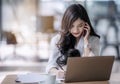 Young asian business woman using laptop and writing on notebook Royalty Free Stock Photo