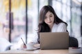 Young asian business woman using laptop and writing on notebook Royalty Free Stock Photo