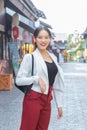 Young Asian business woman wear white suit and red pants smiling confidently,carry bag while walking in the city on a sunny day Royalty Free Stock Photo