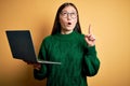 Young asian business woman wearing glasses and working using computer laptop amazed and surprised looking up and pointing with Royalty Free Stock Photo