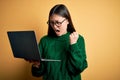 Young asian business woman wearing glasses and working using computer laptop angry and mad raising fist frustrated and furious Royalty Free Stock Photo