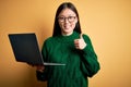 Young asian business woman wearing glasses and working using computer laptop doing happy thumbs up gesture with hand Royalty Free Stock Photo