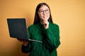 Young asian business woman wearing glasses and working using computer laptop with hand on chin thinking about question, pensive