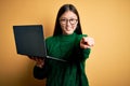 Young asian business woman wearing glasses and working using computer laptop pointing to you and the camera with fingers, smiling Royalty Free Stock Photo