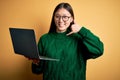 Young asian business woman wearing glasses and working using computer laptop smiling doing phone gesture with hand and fingers Royalty Free Stock Photo