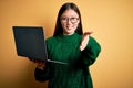 Young asian business woman wearing glasses and working using computer laptop smiling friendly offering handshake as greeting and Royalty Free Stock Photo