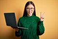 Young asian business woman wearing glasses and working using computer laptop smiling looking to the camera showing fingers doing Royalty Free Stock Photo