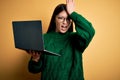 Young asian business woman wearing glasses and working using computer laptop surprised with hand on head for mistake, remember