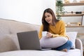 Young asian business woman work from home with laptop computer and drinking coffee on sofa in living room, freelance girl using Royalty Free Stock Photo