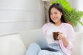 Young asian business woman work from home with laptop computer and drinking coffee on sofa in living room. Royalty Free Stock Photo