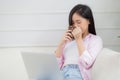 Young asian business woman work from home with laptop computer and drinking coffee on sofa in living room. Royalty Free Stock Photo