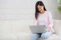 Young asian business woman work from home with laptop computer online to internet on sofa in living room, freelance girl using Royalty Free Stock Photo