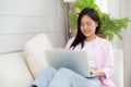 Young asian business woman work from home with laptop computer online to internet on sofa in living room. Royalty Free Stock Photo