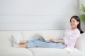 Young asian business woman work from home with laptop computer online to internet on sofa in living room. Royalty Free Stock Photo