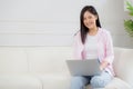 Young asian business woman work from home with laptop computer online to internet on sofa in living room. Royalty Free Stock Photo