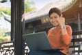 Young asian business woman working with his laptop and enjoying his online winner success on a bench in the park outdoors on Royalty Free Stock Photo