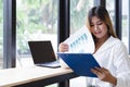 Young asian business woman working with laptop and analyzing business report document in co-working or coffee shop. Business peopl Royalty Free Stock Photo
