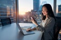 Young Asian business woman working on laptop using mobile at night in office. Royalty Free Stock Photo