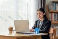 Young Asian business woman working in the office and using her laptop in her office with paper house Royalty Free Stock Photo