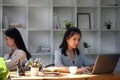 Young asian business woman working with laptop computer while sitting with her colleague in office Royalty Free Stock Photo