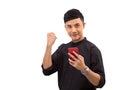 Young Asian businessman in black shirt holding mobile phone and feeling happiness on white background Royalty Free Stock Photo