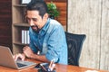 Young Asian businessman in casual clothes stitting and replying an e-mail. Handsome 30s man working at home Royalty Free Stock Photo