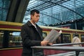 Young Asian businessman confidently reading newspaper at city subway station Royalty Free Stock Photo