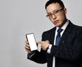 Young asian businessman expert analyst in official jacket, tie and glasses points finger at blank smartphone screen Royalty Free Stock Photo