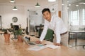 Young Asian businessman leaning on his desk using a laptop Royalty Free Stock Photo