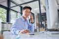 Young asian businessman making a call on his cellphone. Happy businessman typing on his computer. Business professional Royalty Free Stock Photo