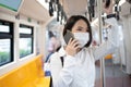 A young Asian businessman in a mask uses a phone in the subway while there is an outbreak of COVID-19 in the country. Concept of