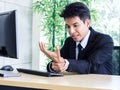 Young Asian businessman pain while using notebook computer in office