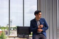 Young Asian businessman sit on a desk in a comfortable position. And the hands were buttoned up on the sleeves