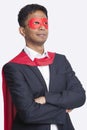 Young Asian businessman in superhero`s costume with arms crossed against white background