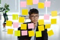 Young asian businessman thinking while reading sticky notes at office, business brainstorming creative planing ideas to success in Royalty Free Stock Photo