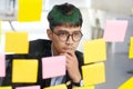 Young asian businessman thinking while reading sticky notes at office, business brainstroming creative planing ideas to success in Royalty Free Stock Photo