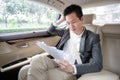 Young asian businessman using tablet and looking out of window while sitting on the back seat in the car. Royalty Free Stock Photo