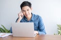Young Asian businessman wear blue shirt talking on mobile phone and working on his laptop in office Royalty Free Stock Photo
