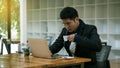 A young Asian businessman who works in front of a laptop and drinks coffee to cure sleepiness in his