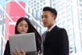 Young Asian Businessman and woman using a laptop together, serious discussion about work while standing in the city, Royalty Free Stock Photo