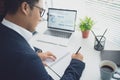 Young Asian businessman work in the office. He was sitting at a white desk using his laptop and taking notes Royalty Free Stock Photo