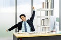 Young asian businessman working at desk in office stretching his arms at workplace Royalty Free Stock Photo